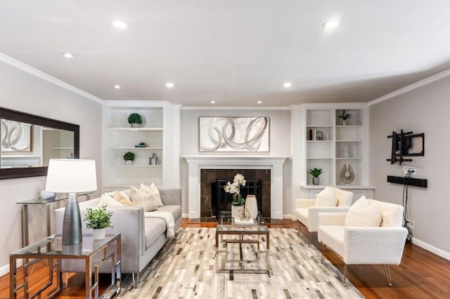 living room with crown molding, a tile fireplace, and light hardwood / wood-style flooring