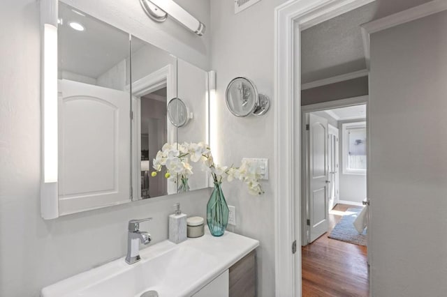 bathroom with crown molding, vanity, and hardwood / wood-style flooring