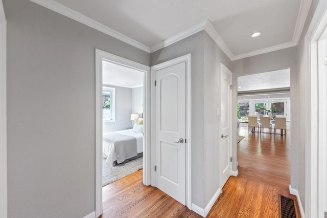 corridor with light hardwood / wood-style floors and crown molding