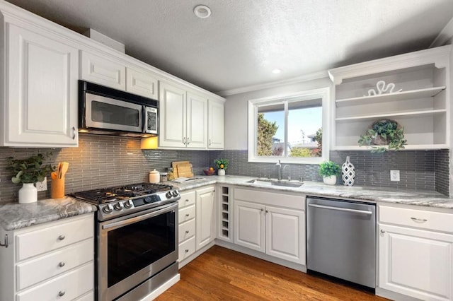 kitchen featuring sink, dark hardwood / wood-style floors, decorative backsplash, white cabinets, and appliances with stainless steel finishes