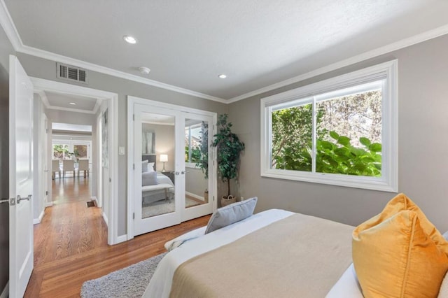 bedroom with multiple windows, crown molding, and wood-type flooring