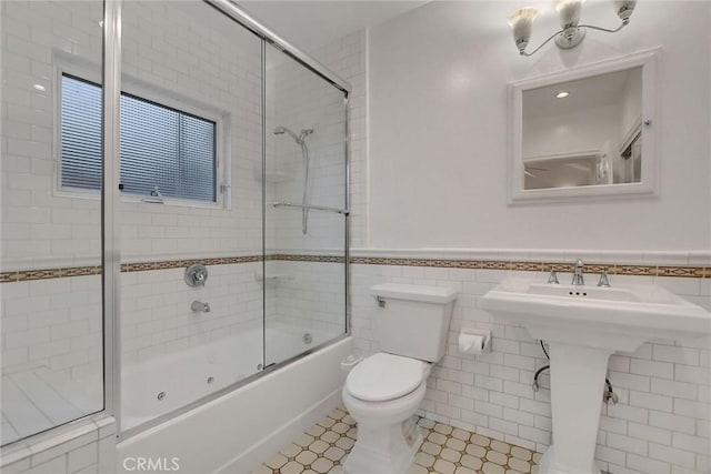 full bathroom with toilet, tile walls, tile patterned flooring, sink, and enclosed tub / shower combo