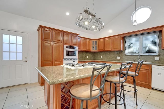 kitchen featuring light tile patterned floors, pendant lighting, a center island, and white appliances