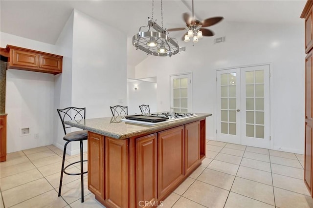 kitchen featuring light stone countertops, french doors, vaulted ceiling, ceiling fan, and light tile patterned floors