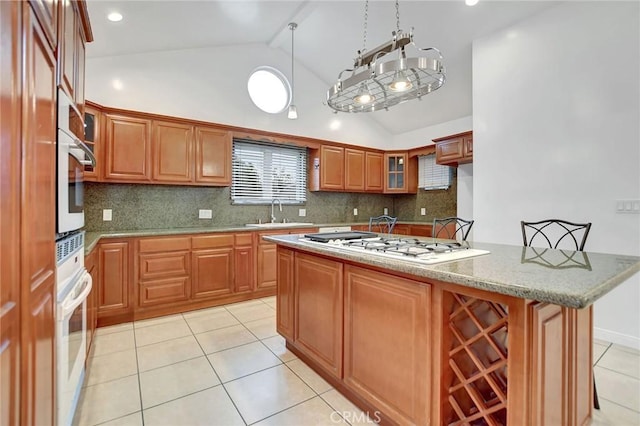 kitchen with tasteful backsplash, a center island with sink, sink, stainless steel gas cooktop, and a kitchen breakfast bar