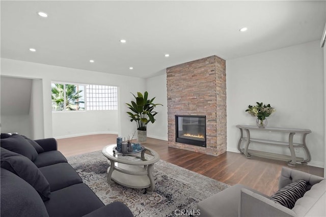 living room with a stone fireplace and hardwood / wood-style flooring