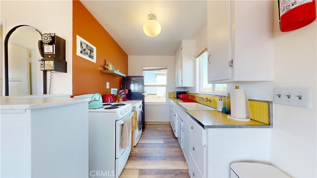 kitchen featuring washer / clothes dryer, white range oven, sink, white cabinets, and light hardwood / wood-style floors