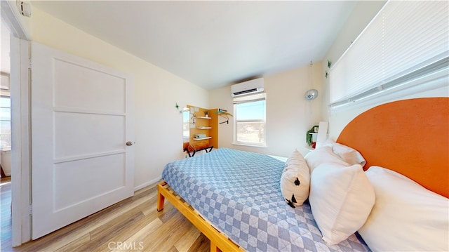 bedroom with an AC wall unit and light hardwood / wood-style flooring