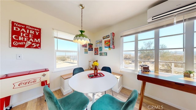 dining room with a wall mounted air conditioner, a wealth of natural light, and light wood-type flooring