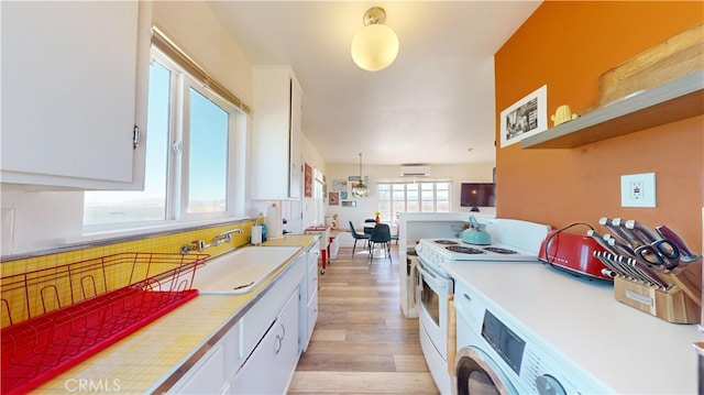 kitchen with white cabinets, hanging light fixtures, white electric range, light hardwood / wood-style floors, and sink