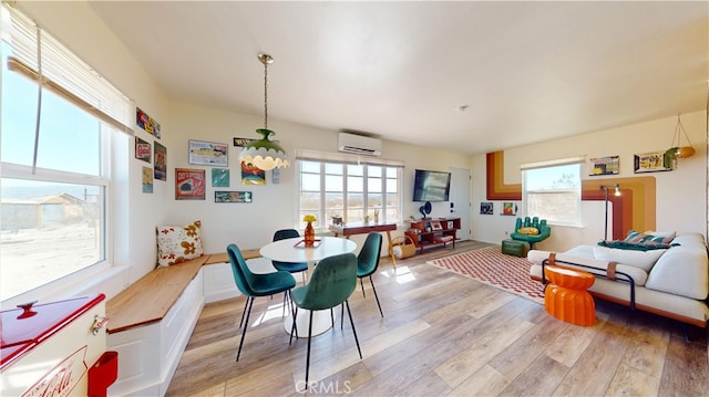 dining room with an AC wall unit, light hardwood / wood-style floors, and plenty of natural light