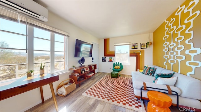 living room with a wall mounted AC, light wood-type flooring, and a wealth of natural light