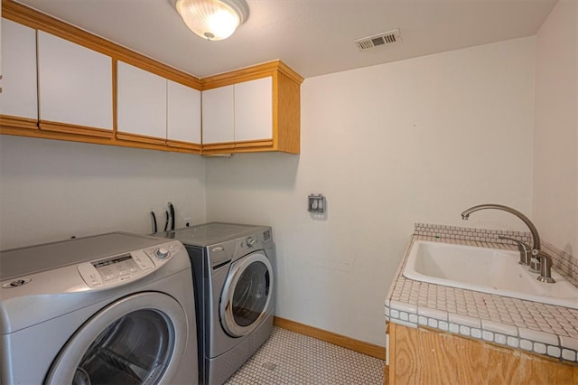 washroom with sink, light tile patterned flooring, separate washer and dryer, and cabinets