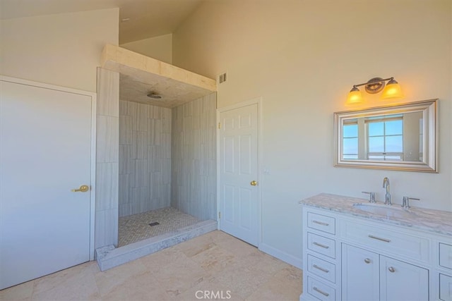 bathroom featuring vanity, high vaulted ceiling, a tile shower, and tile patterned floors