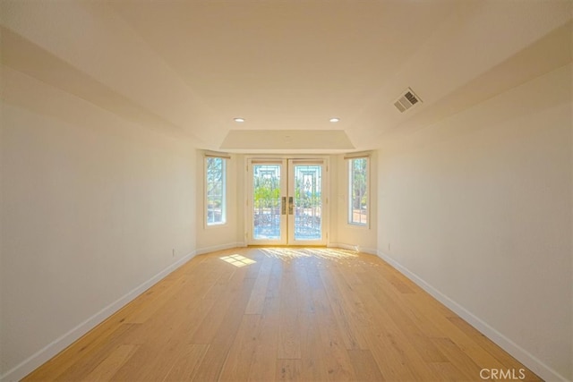 empty room featuring lofted ceiling, french doors, and light hardwood / wood-style flooring