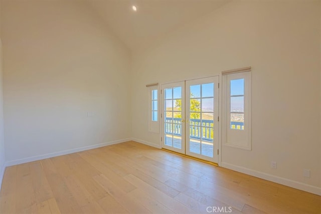 unfurnished room with french doors, high vaulted ceiling, and light wood-type flooring