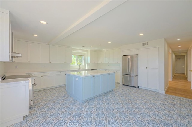 kitchen with range, a center island, white cabinetry, and stainless steel refrigerator