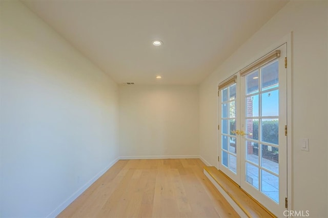 empty room featuring french doors and light hardwood / wood-style flooring