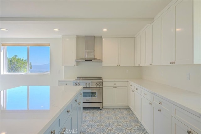 kitchen with white cabinetry, light stone counters, wall chimney exhaust hood, and high end range