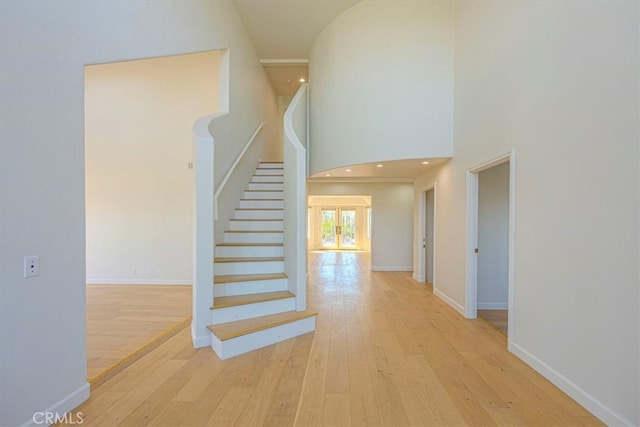 staircase with wood-type flooring and a high ceiling