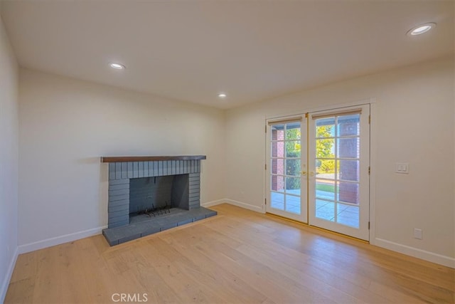 unfurnished living room with french doors, a fireplace, and light hardwood / wood-style floors