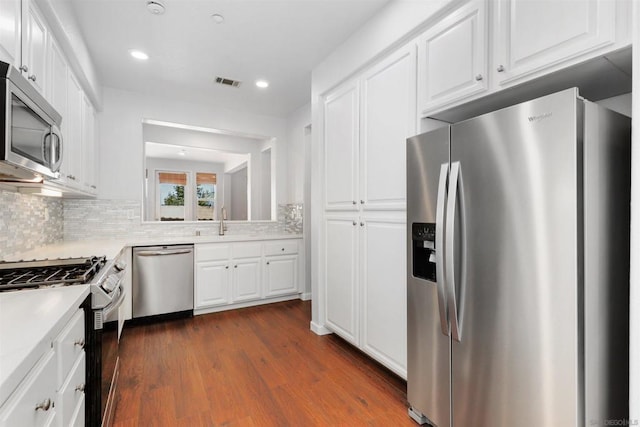 kitchen with backsplash, white cabinets, sink, dark hardwood / wood-style flooring, and stainless steel appliances