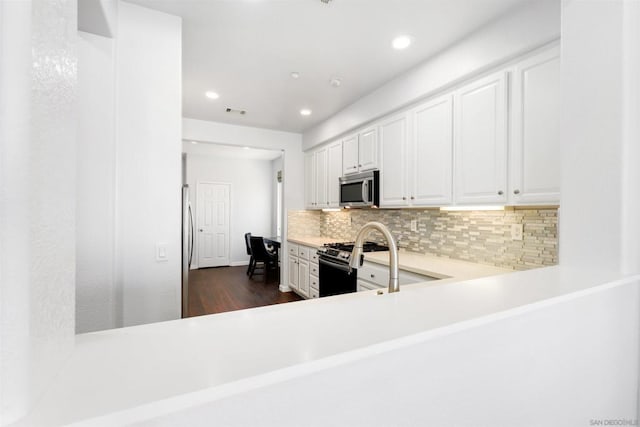 kitchen featuring sink, tasteful backsplash, dark hardwood / wood-style flooring, white cabinetry, and stainless steel appliances