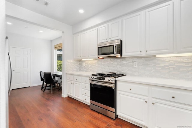 kitchen with white cabinets, dark hardwood / wood-style flooring, stainless steel appliances, and tasteful backsplash