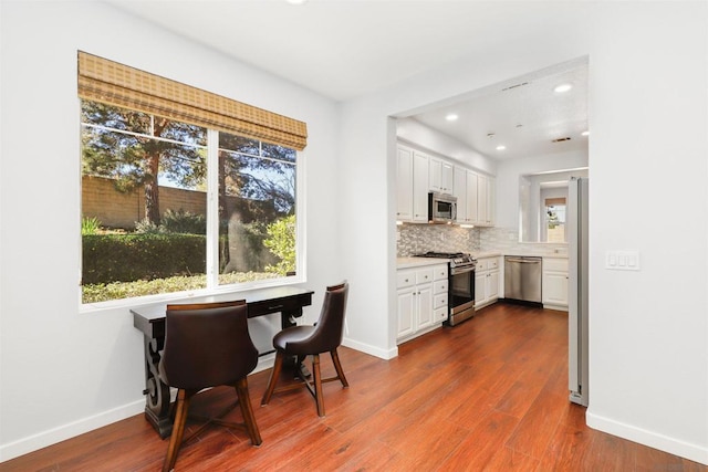 kitchen featuring appliances with stainless steel finishes, backsplash, white cabinetry, and dark wood-type flooring