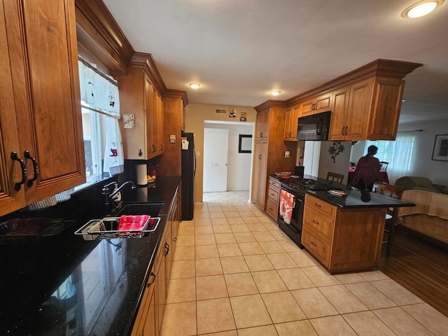 kitchen with light tile patterned floors, black appliances, sink, and a wealth of natural light