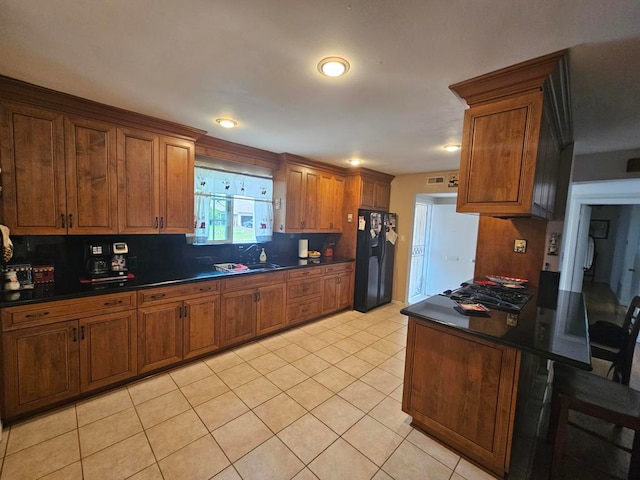 kitchen with tasteful backsplash, light tile patterned floors, black fridge with ice dispenser, gas cooktop, and sink