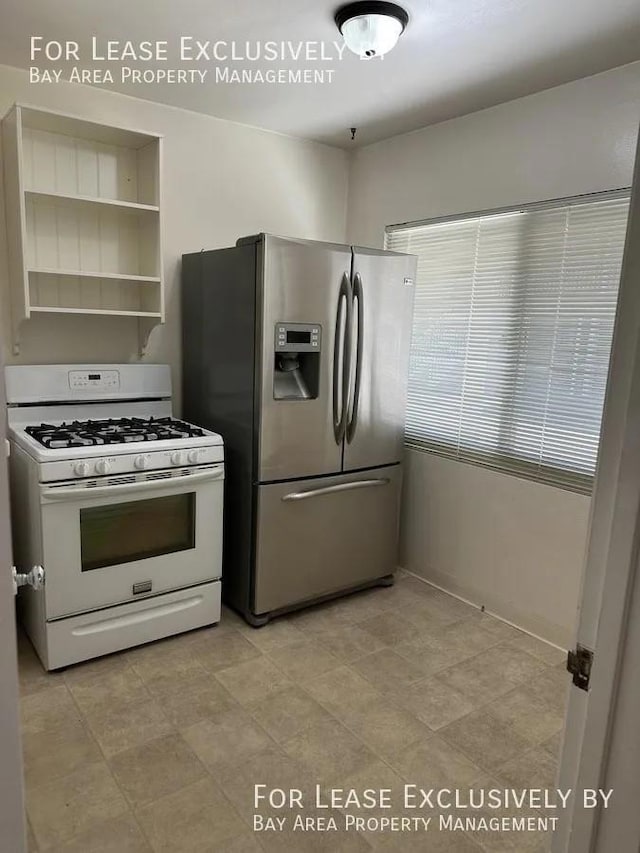 kitchen featuring white range with gas stovetop and stainless steel fridge