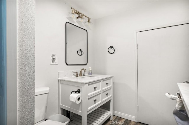 bathroom with hardwood / wood-style floors, vanity, and toilet