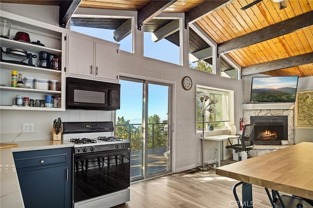 kitchen featuring black microwave, light countertops, open shelves, gas range, and vaulted ceiling with beams