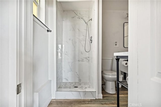 bathroom with toilet, wood-type flooring, and tiled shower