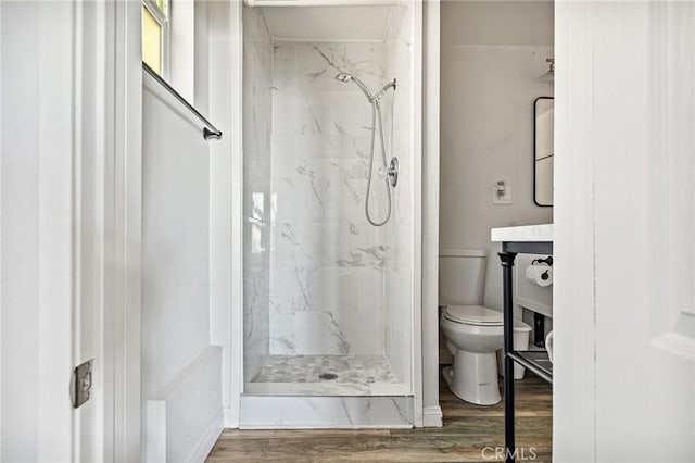 bathroom featuring a marble finish shower, toilet, and wood finished floors