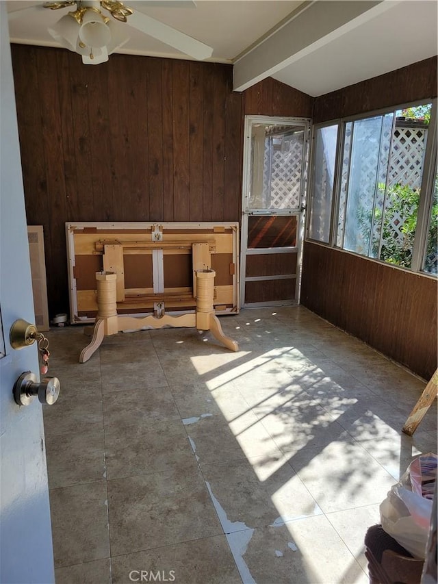 unfurnished sunroom featuring ceiling fan and beamed ceiling