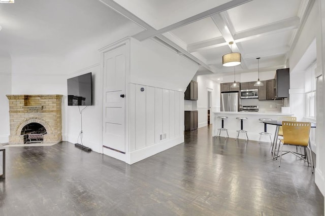 living room featuring beam ceiling, coffered ceiling, and a fireplace