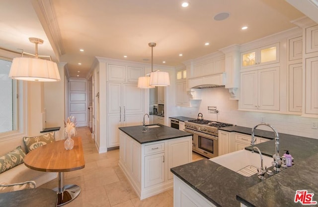 kitchen featuring double oven range, an island with sink, hanging light fixtures, and white cabinets