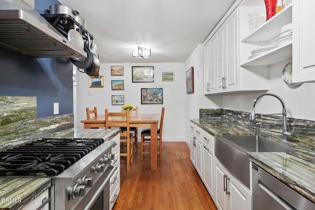 kitchen with dark stone countertops, white cabinetry, hardwood / wood-style floors, and appliances with stainless steel finishes