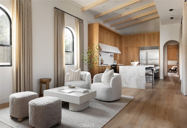 living room with sink, light hardwood / wood-style flooring, and vaulted ceiling with beams