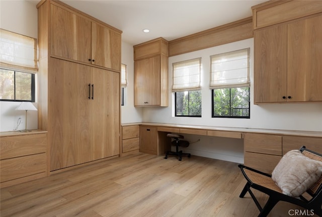 unfurnished office featuring built in desk and light wood-type flooring