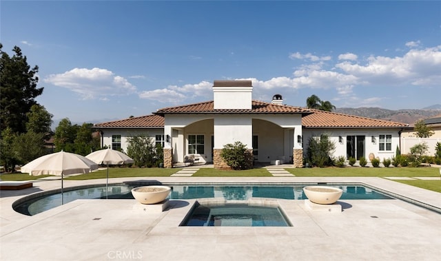 rear view of property featuring a patio area, a lawn, and a swimming pool with hot tub