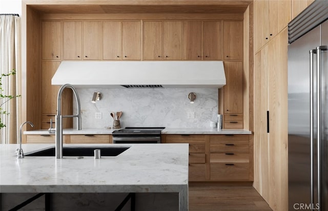 kitchen with light brown cabinets, hardwood / wood-style flooring, sink, appliances with stainless steel finishes, and light stone counters