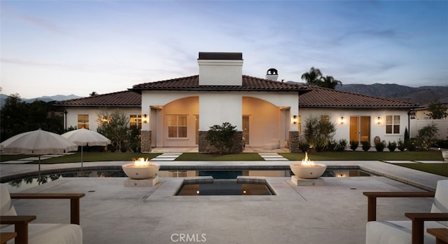 back house at dusk featuring a patio and a mountain view