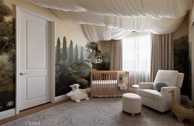 bedroom featuring a nursery area and hardwood / wood-style floors