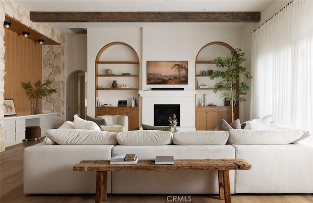 living room with beamed ceiling, hardwood / wood-style floors, and built in shelves