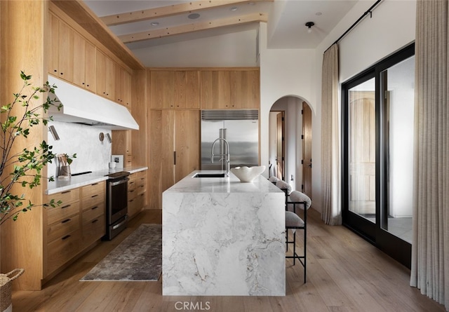 kitchen featuring sink, appliances with stainless steel finishes, a kitchen island with sink, and light hardwood / wood-style floors