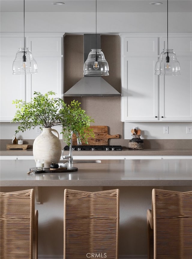 kitchen with white cabinetry, wall chimney range hood, decorative light fixtures, and gas stovetop