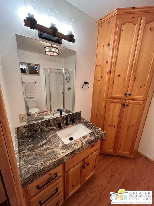 bathroom with vanity, walk in shower, hardwood / wood-style flooring, and toilet